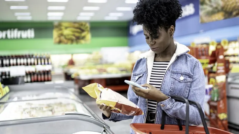 Mulher fazendo compras no supermercado e scanneando o código de barras com o smartphone (Foto: iStock)